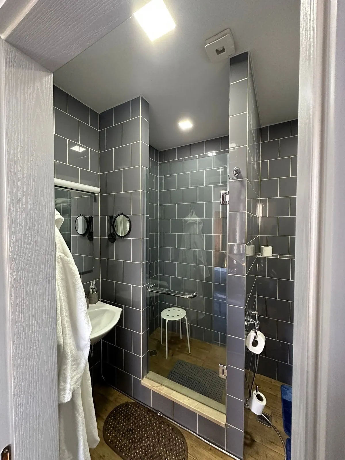 Grey-tiled bathroom with rain shower and robe