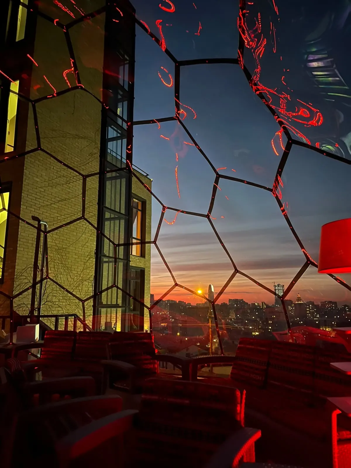 Inside the geodesic dome at sunset, with red lounge seating and Batumi glowing below